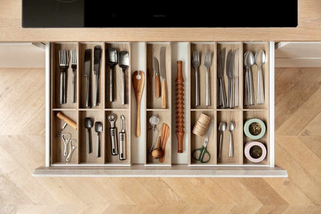 A cutlery drawer with wooden drawer inserts and black and silver cutlery.